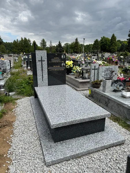 Nagrobek z jasnej płyty Tarn i czarnej steli Impala z portretem, ujęcie na tle dramatycznego pochmurnego nieba, cmentarz Kraków, Kamileo.
