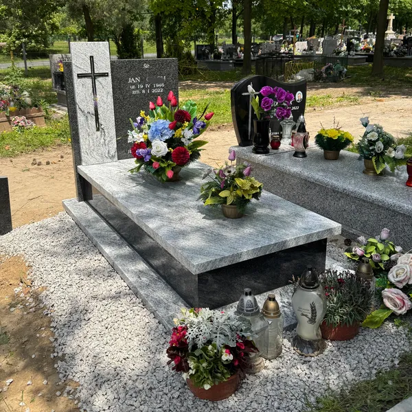 Nagrobek z jasnej płyty Viscount White z czarną stelą Impala i metalowym krzyżem, bukiety kwiatów, cmentarz Kraków, realizacja Kamileo.