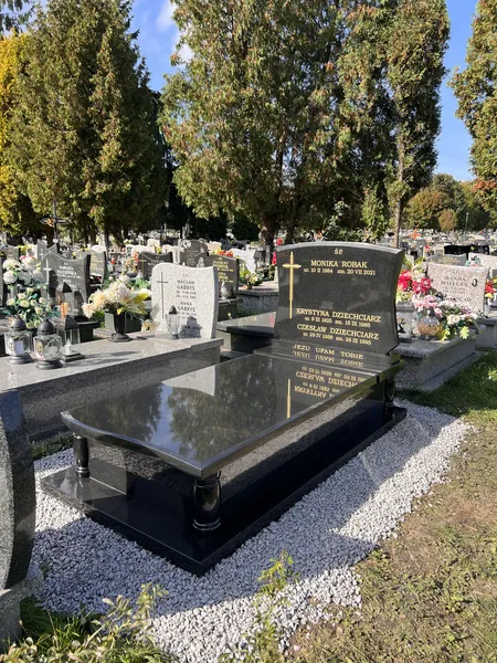 Czarny sarkofag z granitu Monumental z ozdobnymi tokarskimi nóżkami i wieloosobową inskrypcją, cmentarz Kraków, realizacja Kamileo.