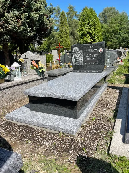Nagrobek Tarn Impala z falistą krawędzią płyty i czarną stelą z płaskorzeźbą postaci, cmentarz Kraków, realizacja Kamileo.