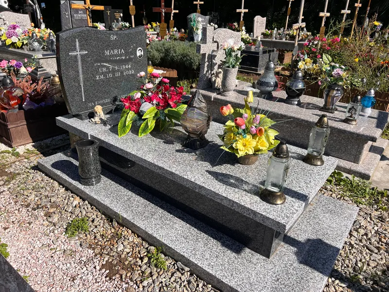 Nagrobek Tarn Impala z czarną stelą, granitowymi wazonami i bogatą oprawą kwiatową na cmentarzu w Krakowie, realizacja Kamileo.