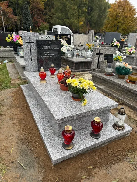 Nagrobek Tarn Impala z czarną stelą granitową i inskrypcją, jesienne otoczenie cmentarza Kraków z chryzantemami, realizacja Kamileo.