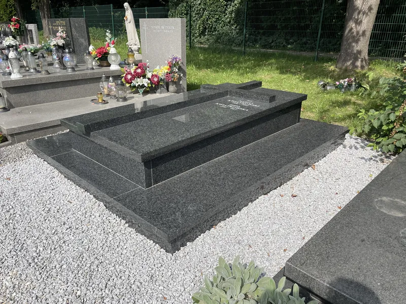 Podwójny grobowiec w formie sarkofagu z czarnego granitu Impala z pochyloną tablicą inskrypcyjną na cmentarzu, realizacja Kamileo Kraków.